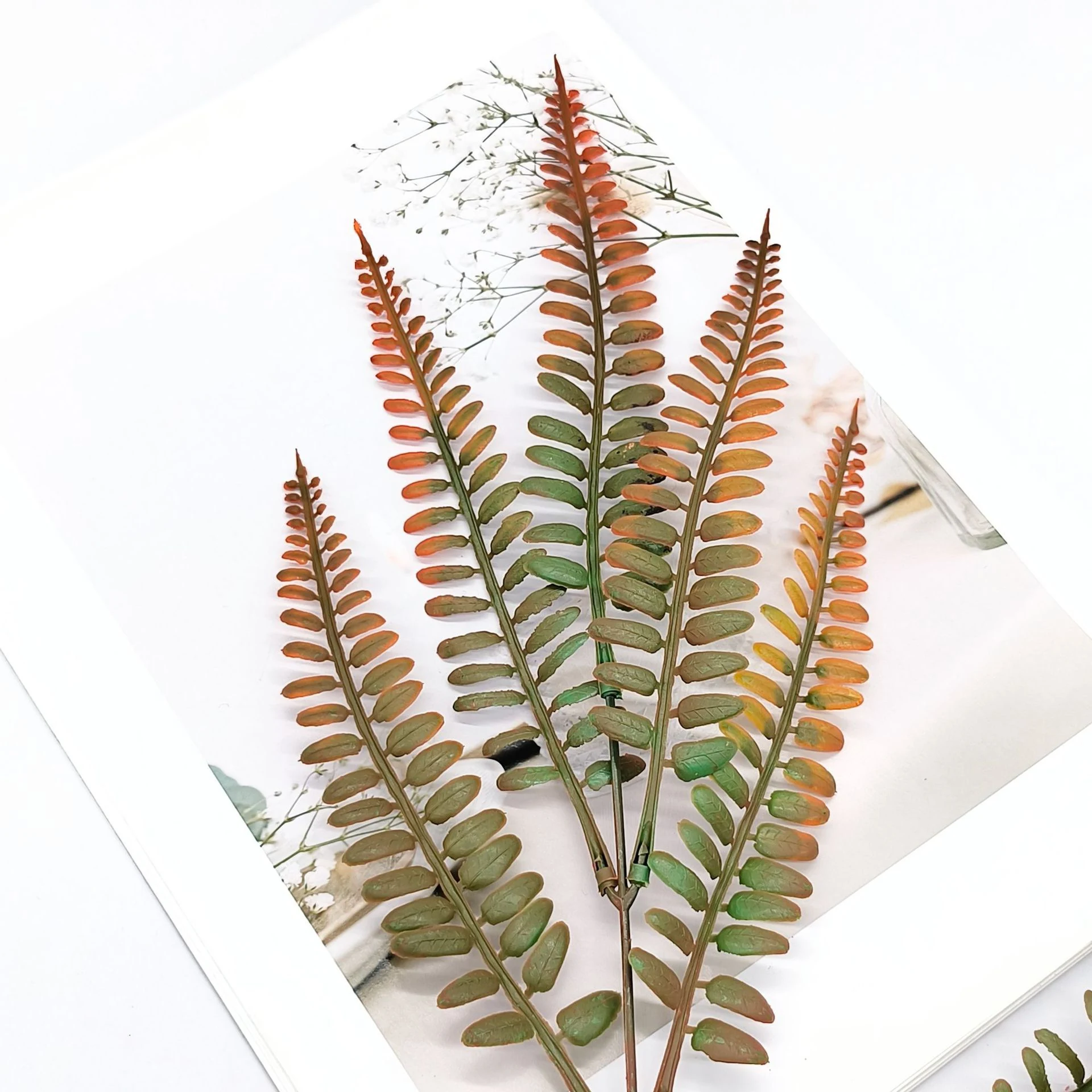 Close-up of rust orange and olive green fronds on an artificial autumn fern leaf bush