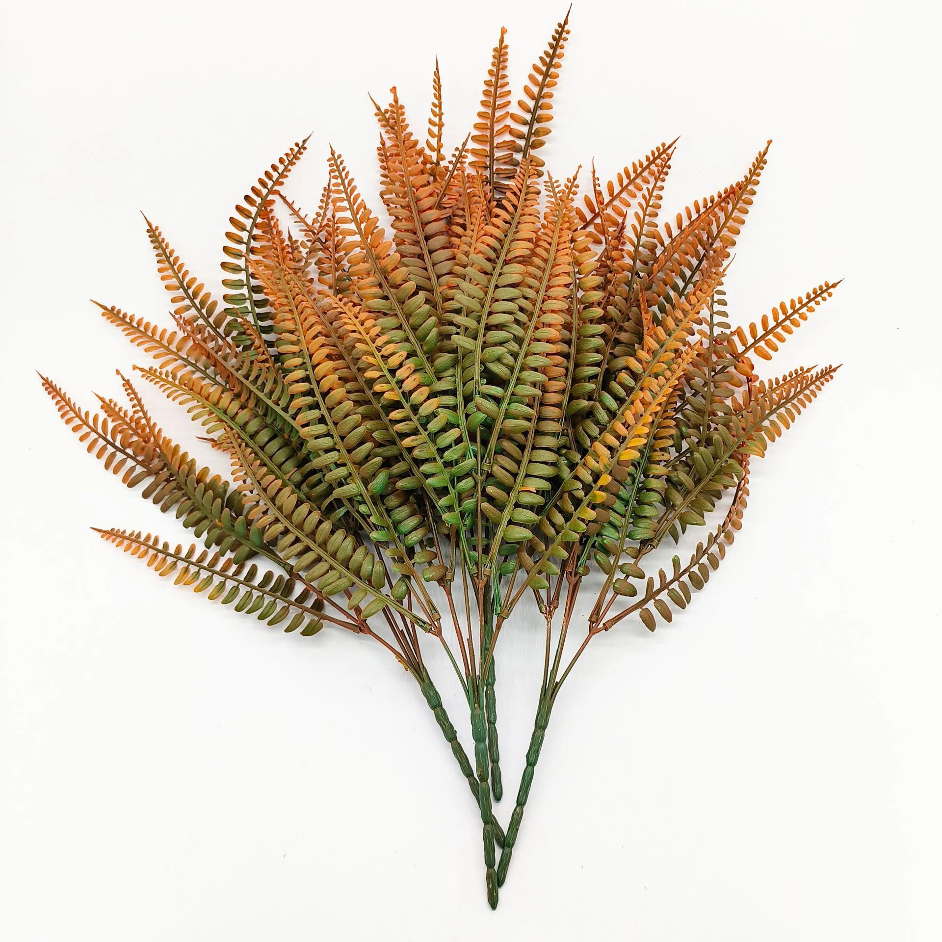 Grouped display of artificial autumn fern leaf bushes in rust orange and olive green
