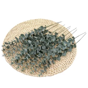 Artificial baby silver dollar eucalyptus stems arranged on a woven mat