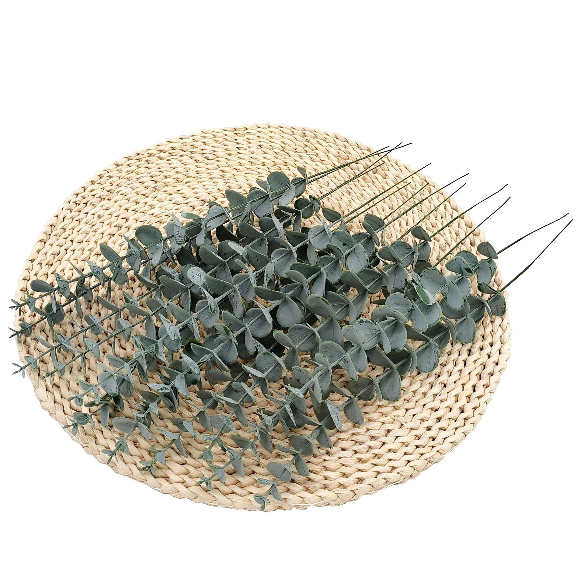 Artificial baby silver dollar eucalyptus stems arranged on a woven mat