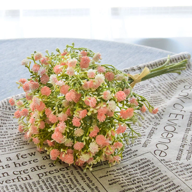 Coral pink artificial baby's breath bouquet arranged on a newspaper backdrop