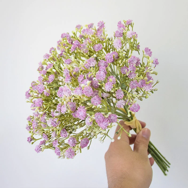 Hand holding a lavender and white artificial baby's breath bouquet