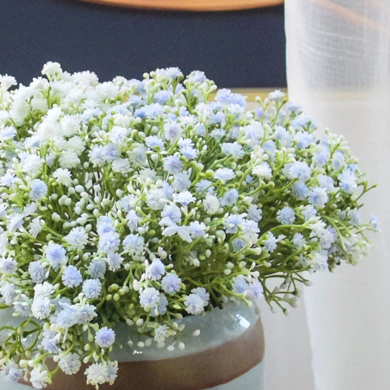 Light blue and white artificial baby's breath flowers arranged in a ceramic vase