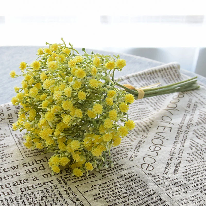 Yellow artificial baby's breath bouquet arranged on a newspaper backdrop