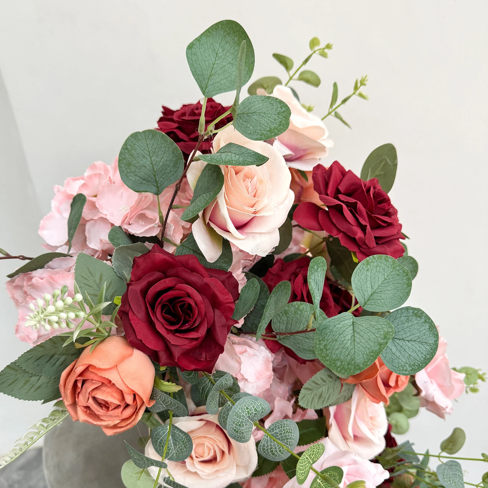 Close-up of burgundy blush artificial cascading wedding table flower arrangement collection