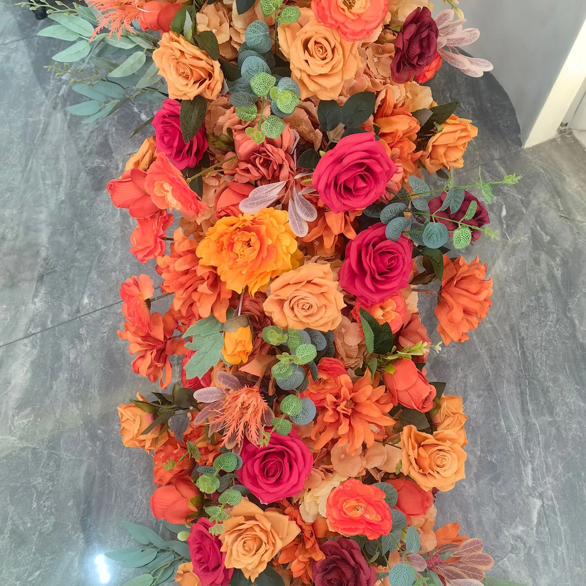 Close-up of orange rose artificial cascading wedding table flower arrangement collection
