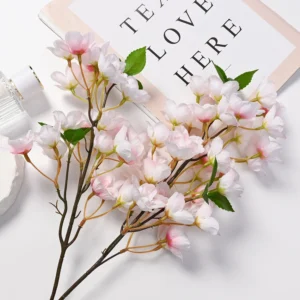 Light pink artificial cherry blossom branch arranged on a tabletop