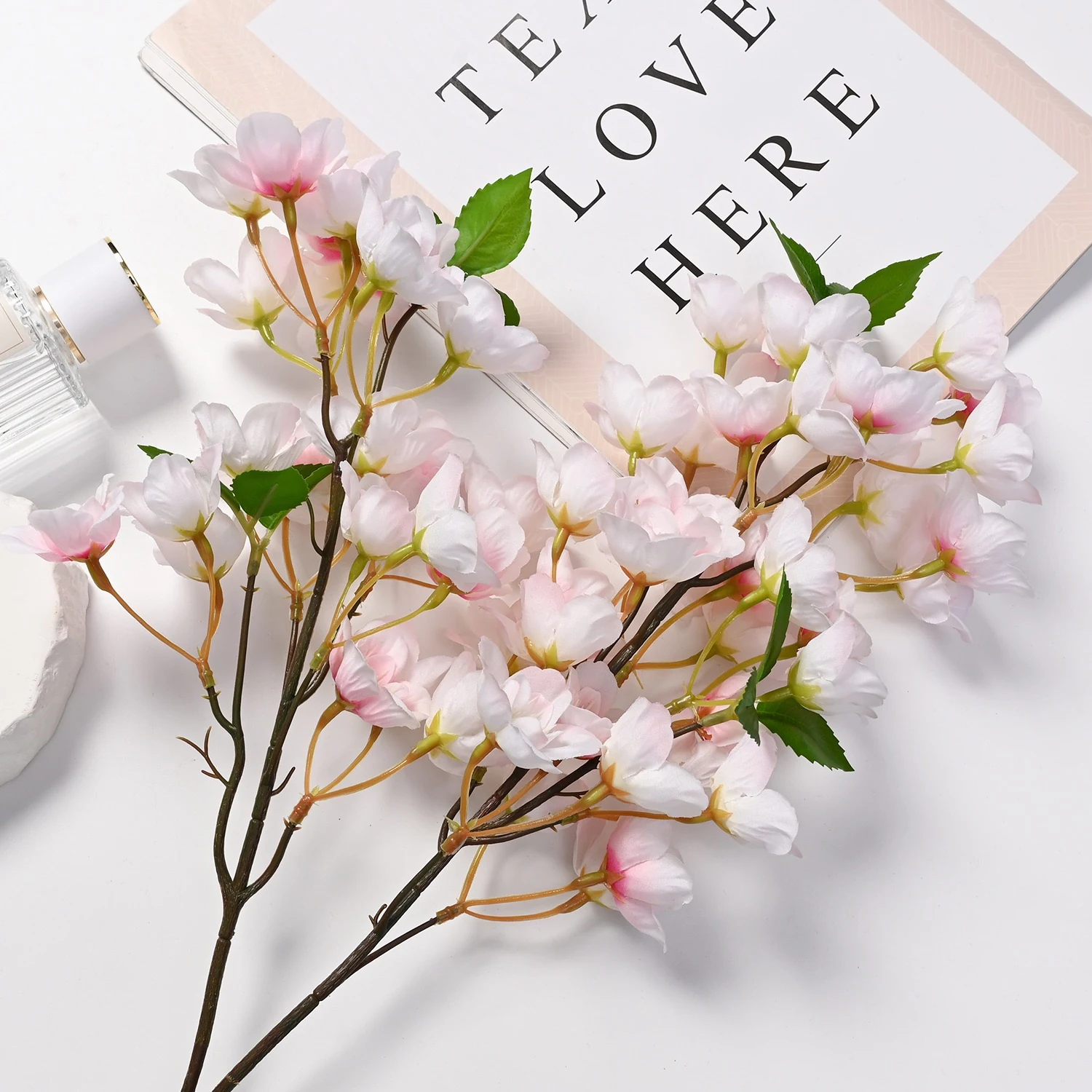 Light pink artificial cherry blossom branch arranged on a tabletop