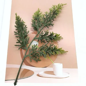 Green artificial cypress branch in a styled mirror display