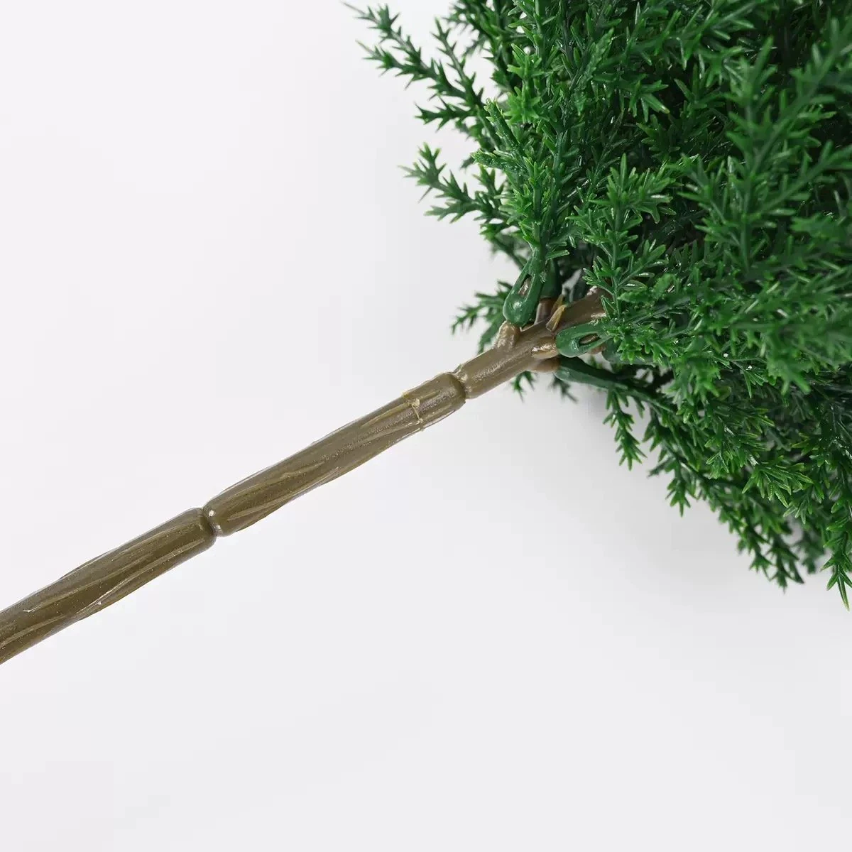 Close-up of the trunk connection beneath artificial cypress foliage