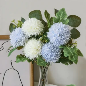 Light blue and white artificial pompon chrysanthemum stems arranged in a glass vase