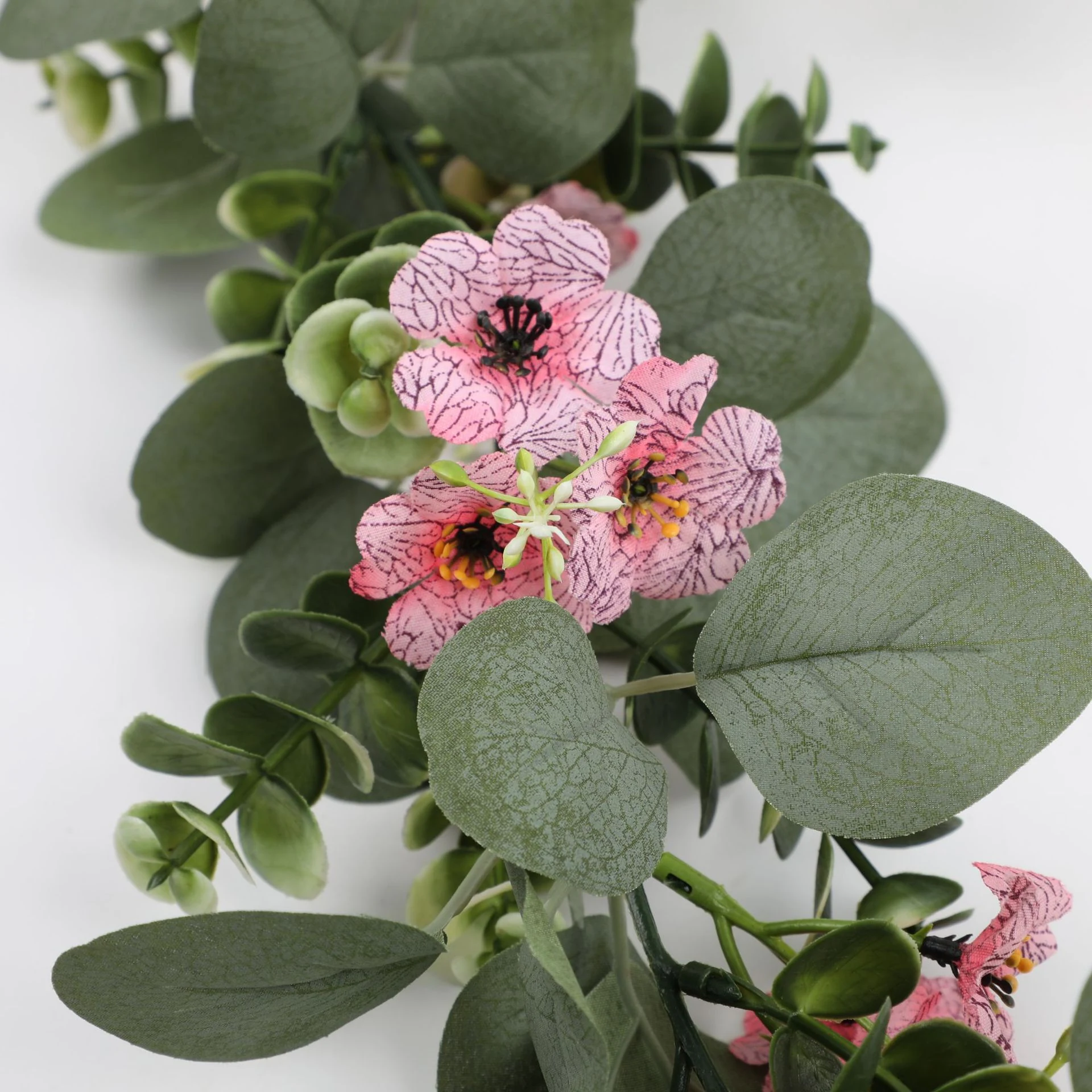 Close-up of pink flowers and rounded eucalyptus leaves on artificial garland