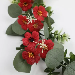 Close-up of red flowers and rounded eucalyptus leaves on artificial garland