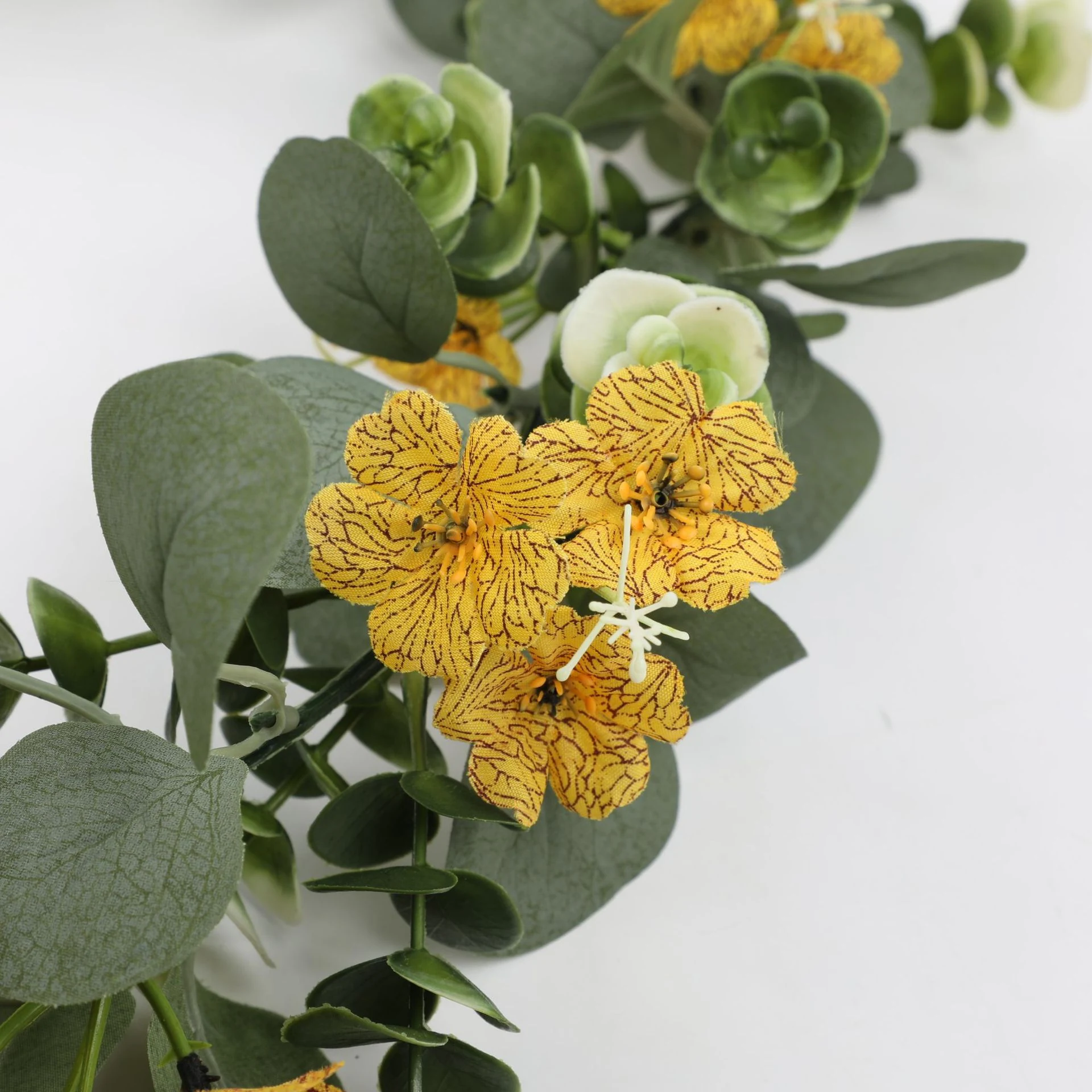 Close-up of yellow flowers and rounded eucalyptus leaves on artificial garland