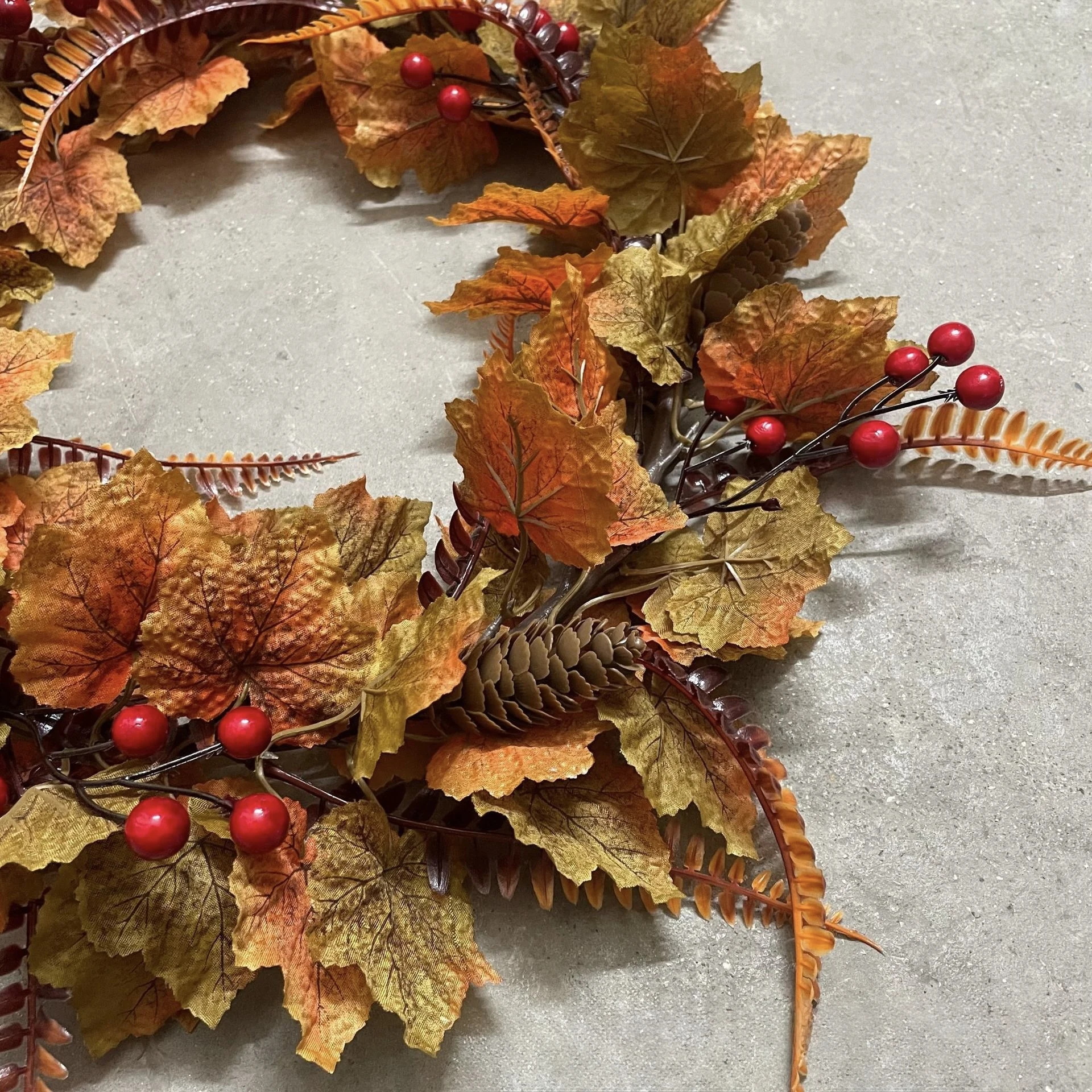 Red berry and pinecone details on artificial fall maple leaf wreath