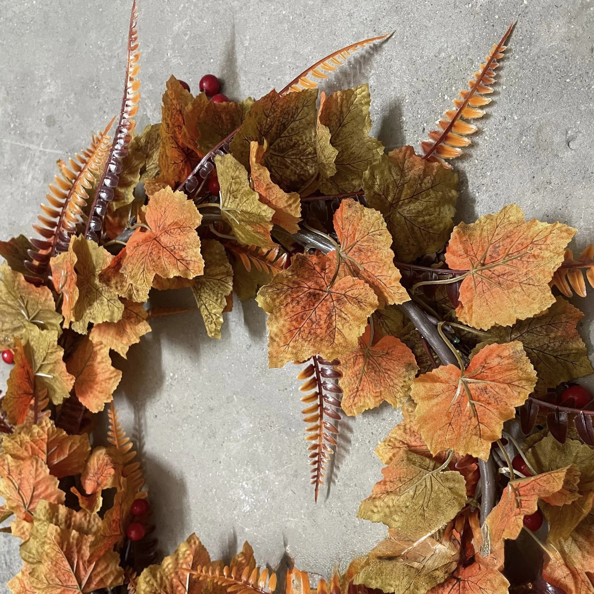 Fern-style foliage accents on artificial fall maple leaf wreath