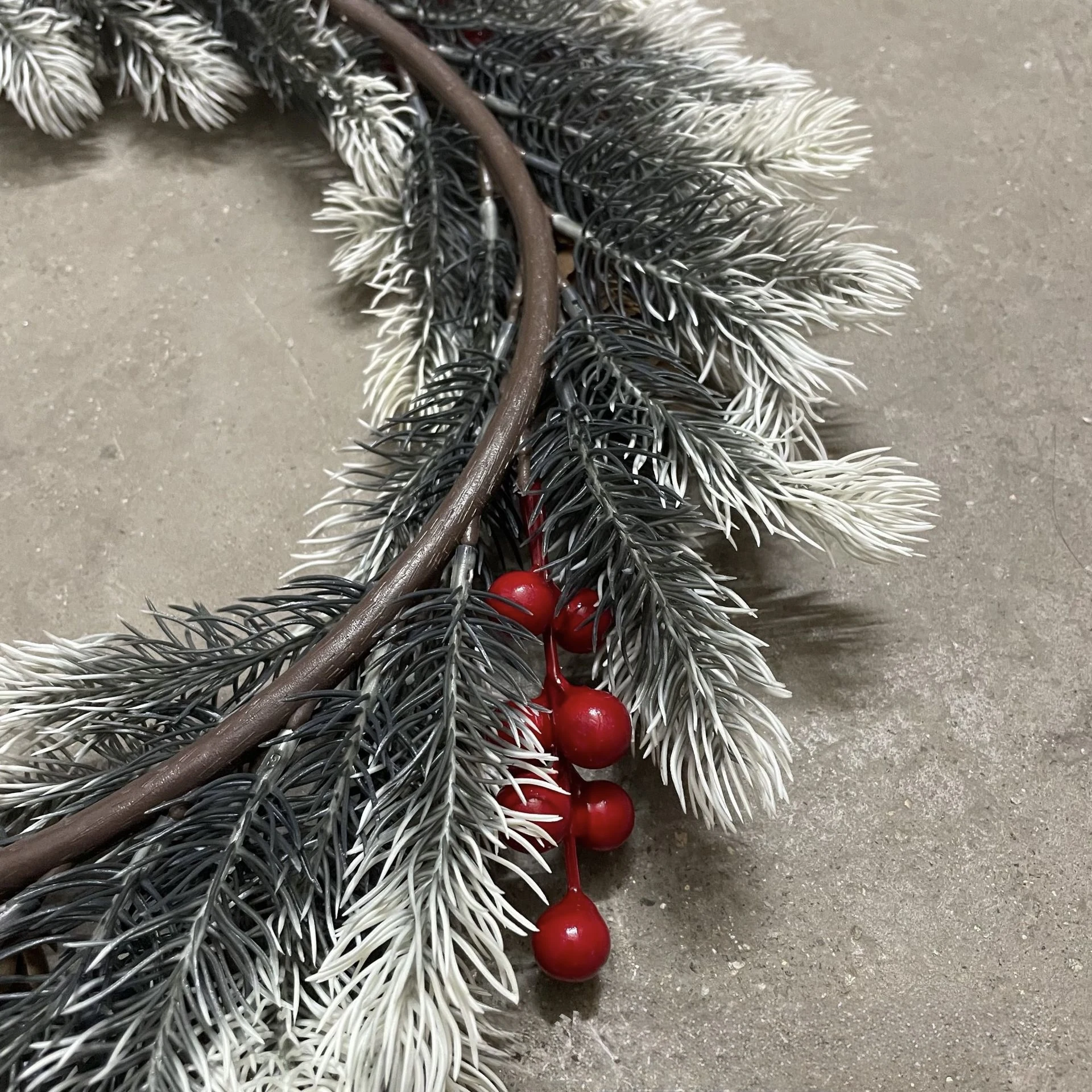 Close-up of red berries and flocked fir foliage on wreath