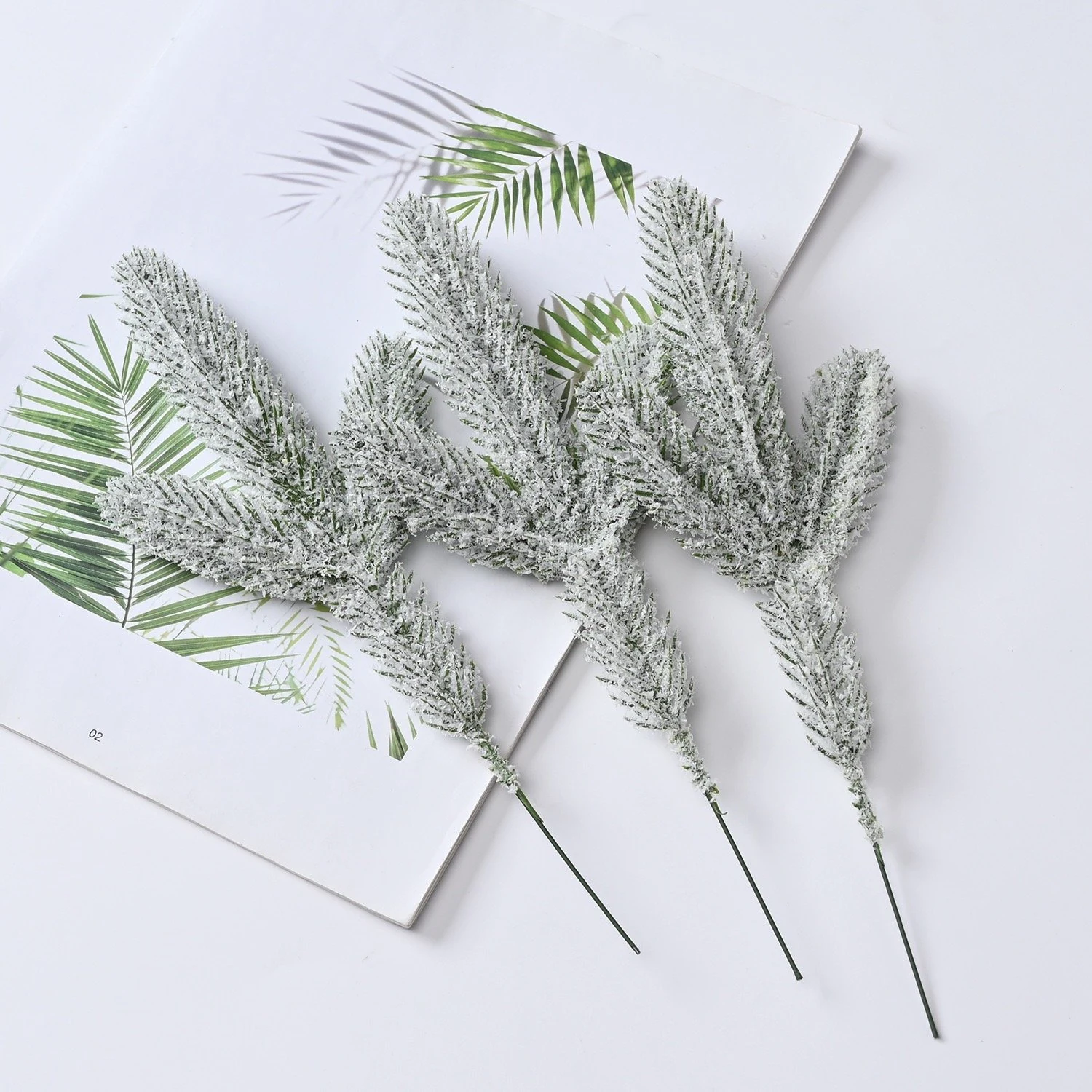 Three artificial frosted pine picks laid flat