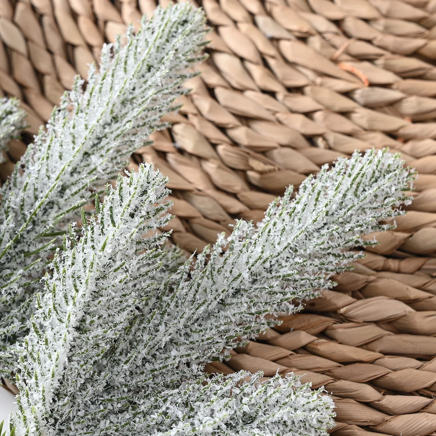 Artificial frosted pine foliage on a woven background