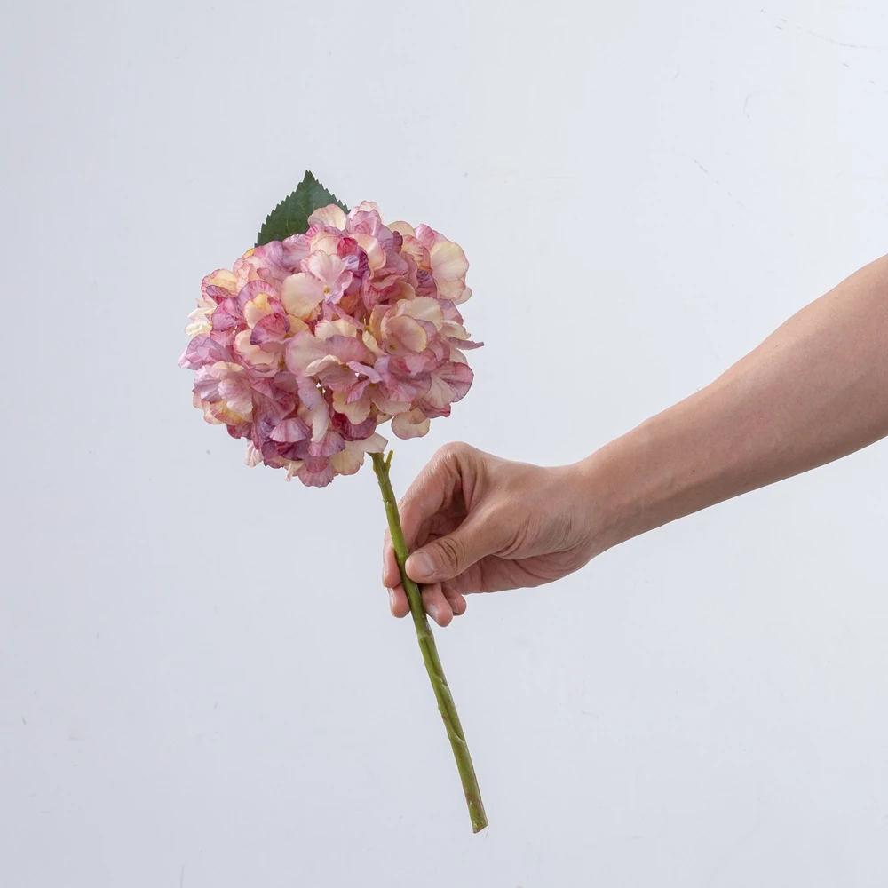 Handheld view of blush pink artificial hydrangea stem