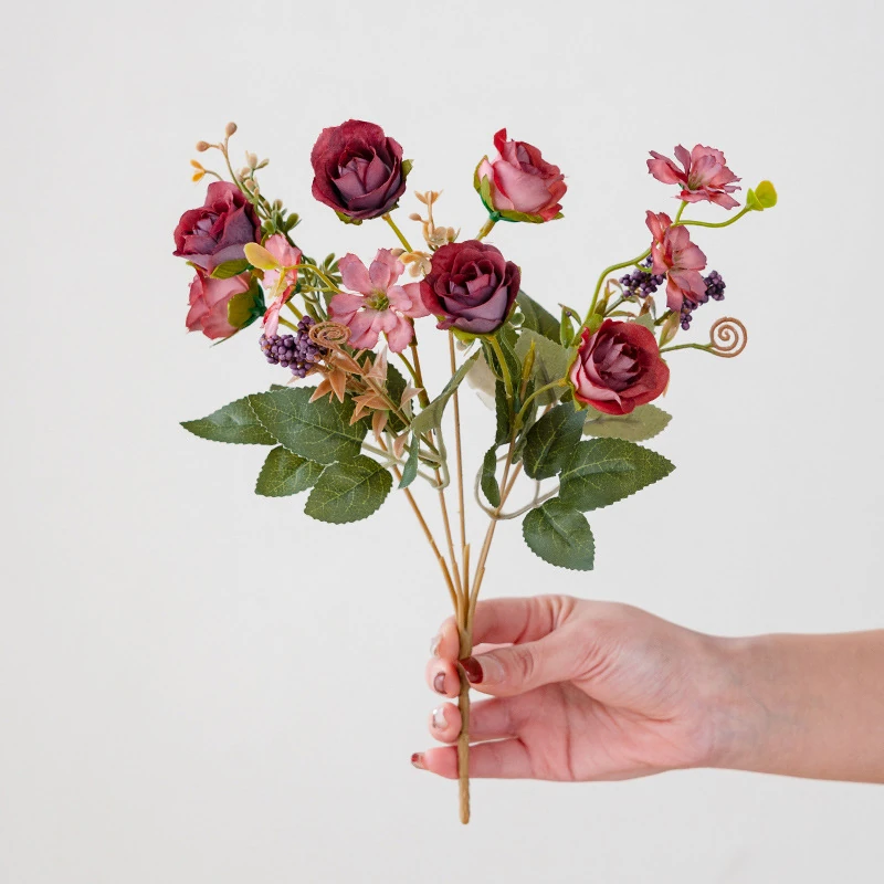 Handheld view of burgundy artificial mini rose mixed flower bouquet