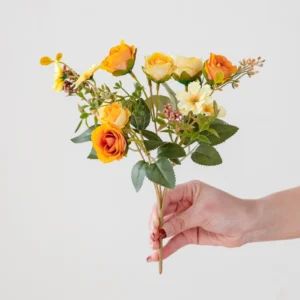 Handheld view of orange artificial mini rose mixed flower bouquet