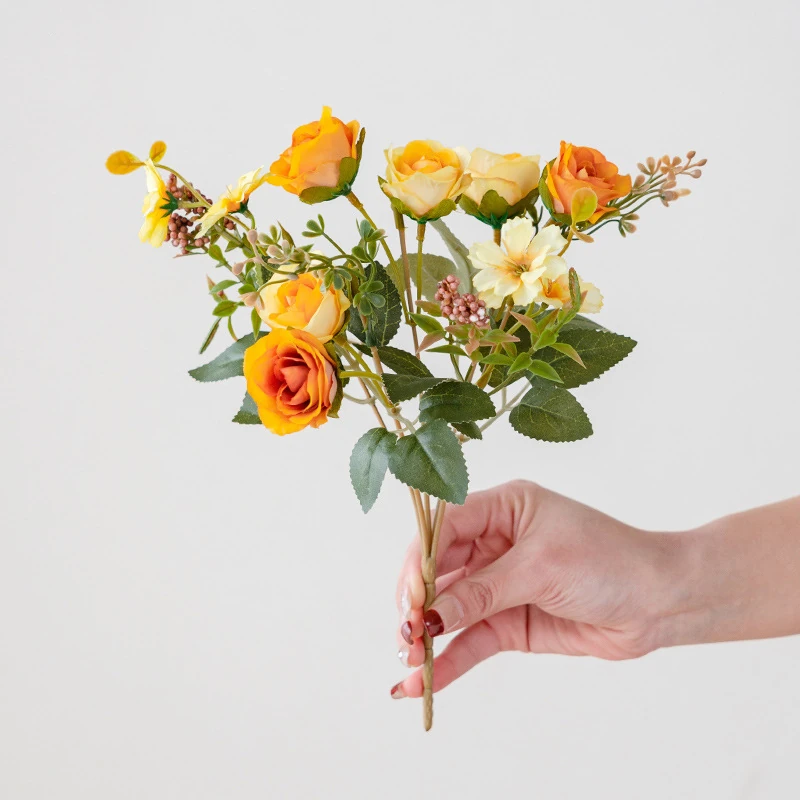 Handheld view of orange artificial mini rose mixed flower bouquet