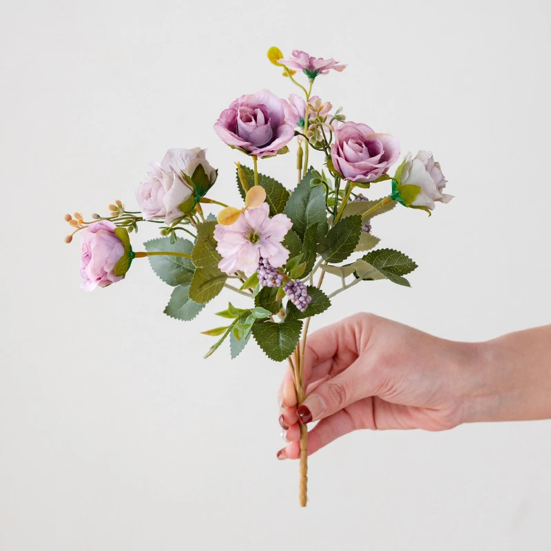 Handheld view of purple artificial mini rose mixed flower bouquet