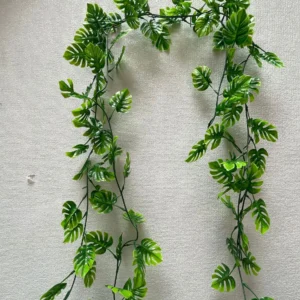 Artificial monstera leaf garland draped on a wall