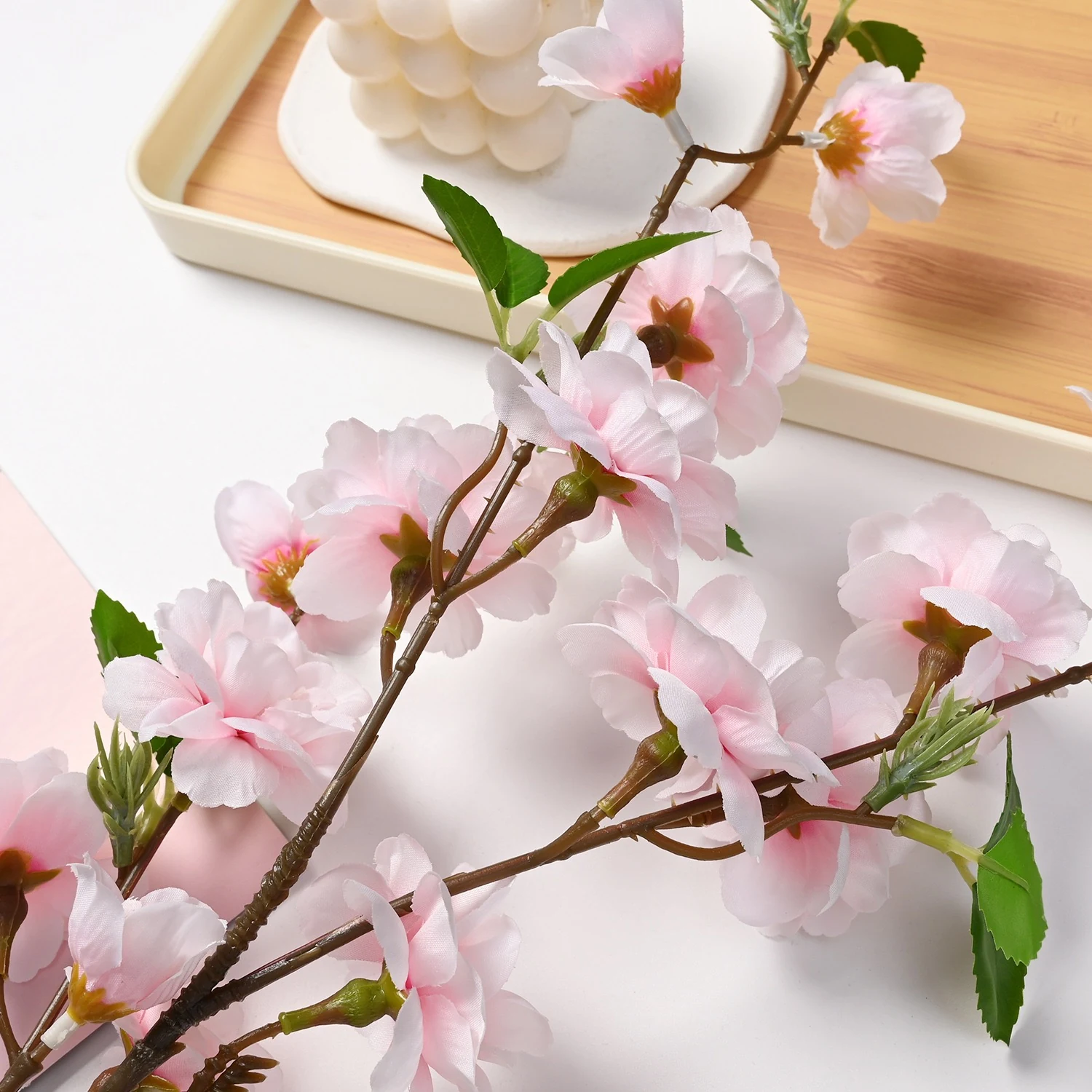 Light pink artificial peach blossom branch in a tabletop tray display