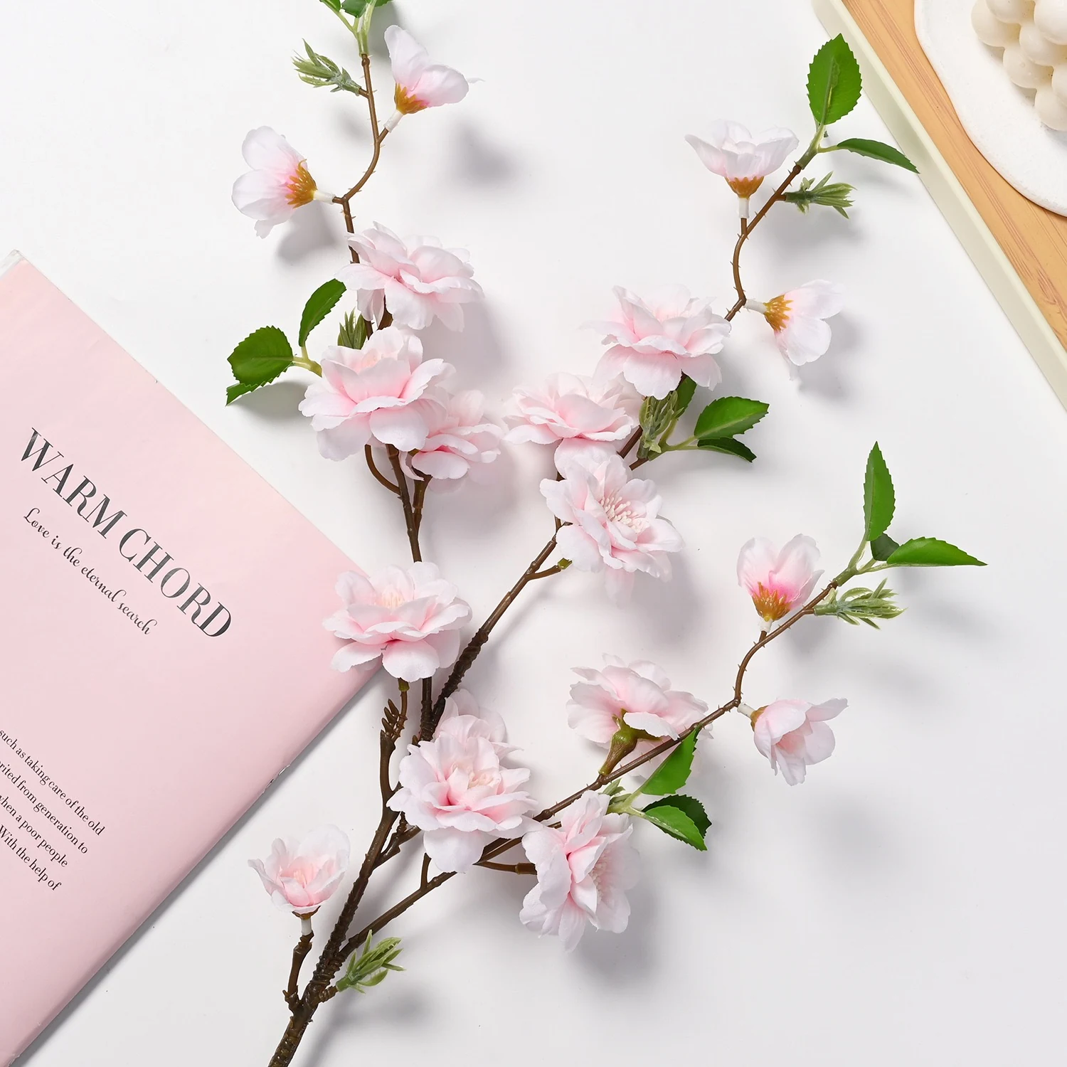 Light pink artificial peach blossom branch styled beside a book