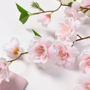 Close-up of light pink artificial peach blossom flowers and leaves