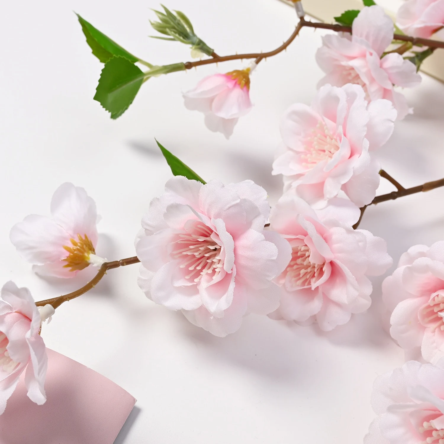 Close-up of light pink artificial peach blossom flowers and leaves