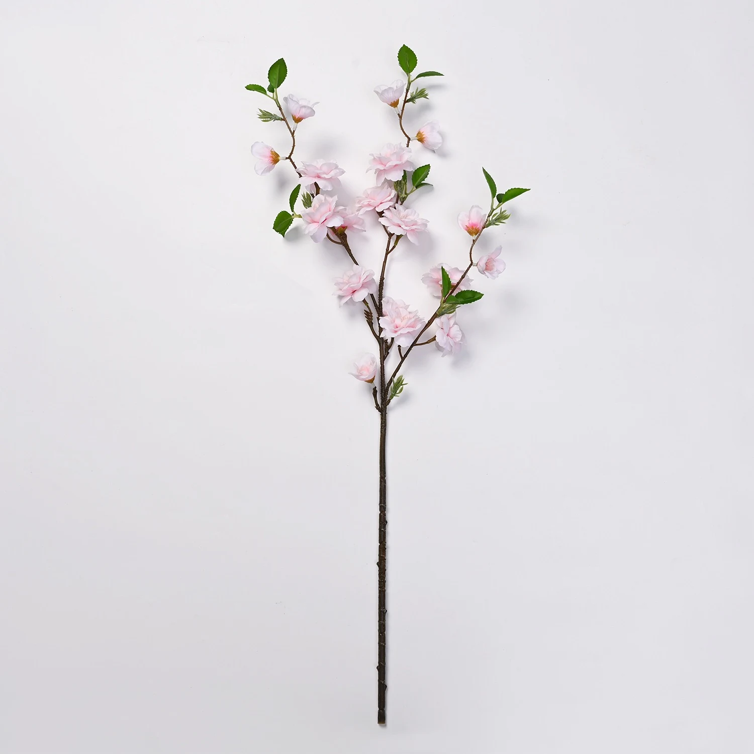 Light pink artificial peach blossom branch on a white background