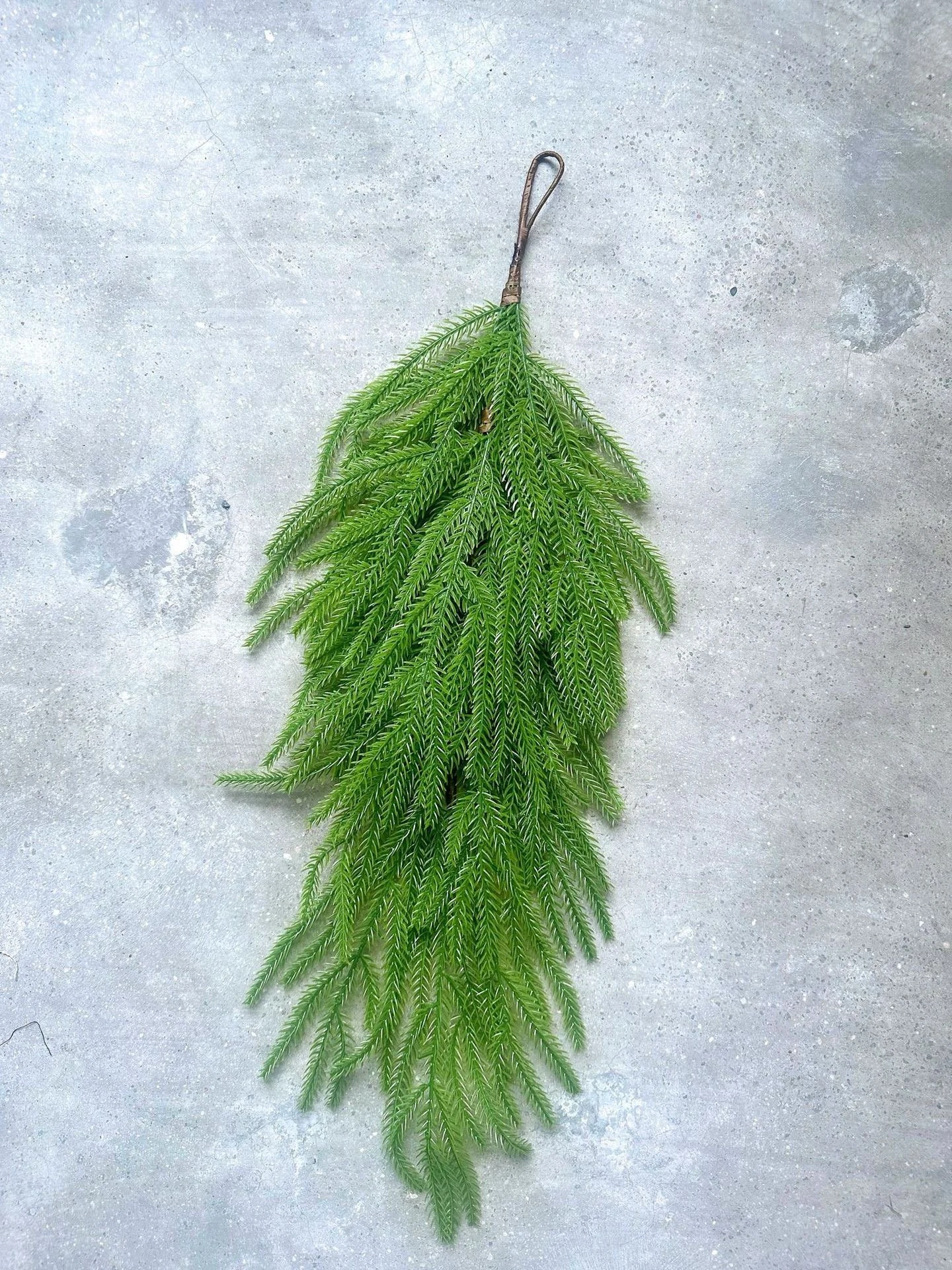 Artificial pine swag displayed vertically by its hanging loop