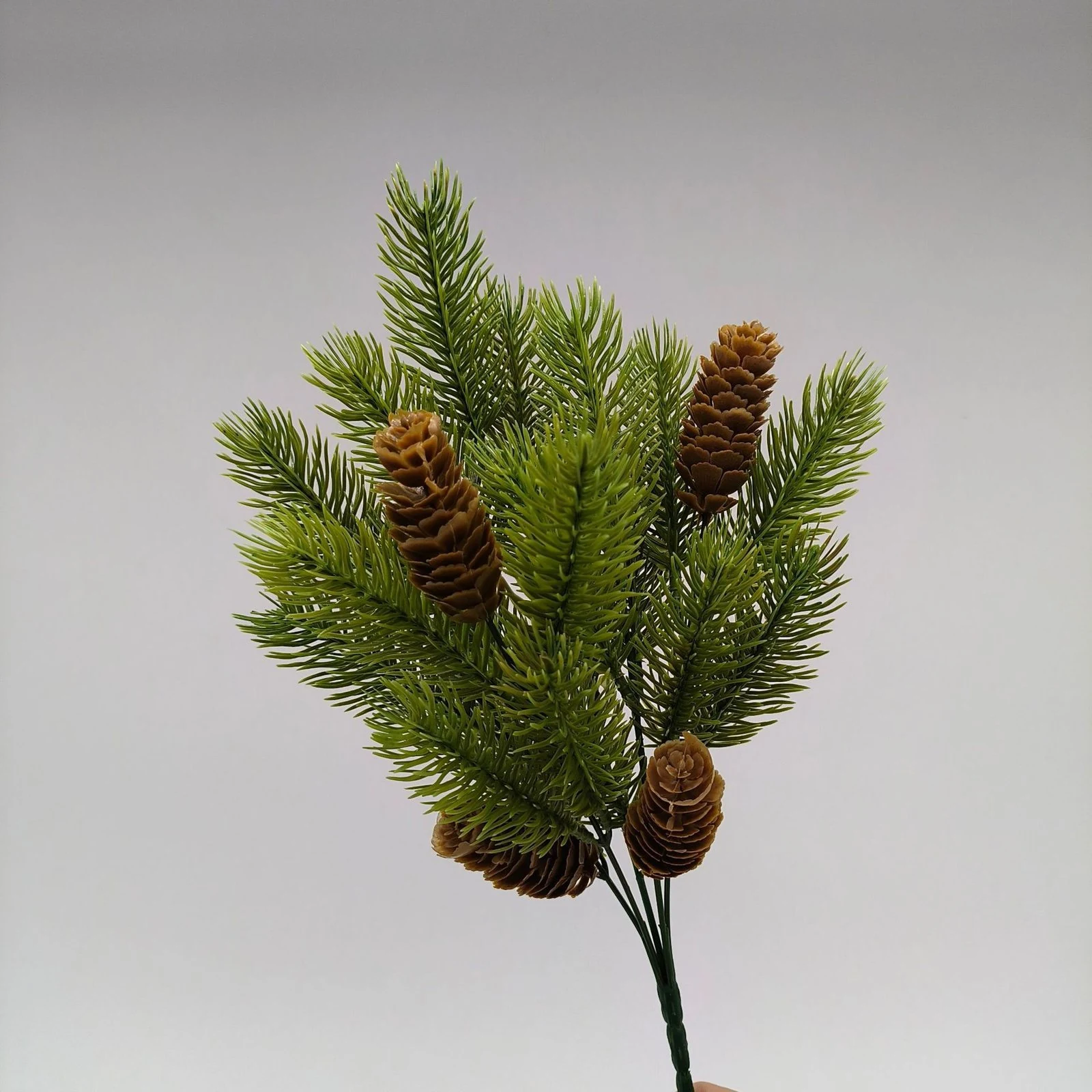 Hand-held side view of artificial pinecone evergreen bush