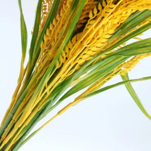 Close-up of golden artificial rice grains and green leaves