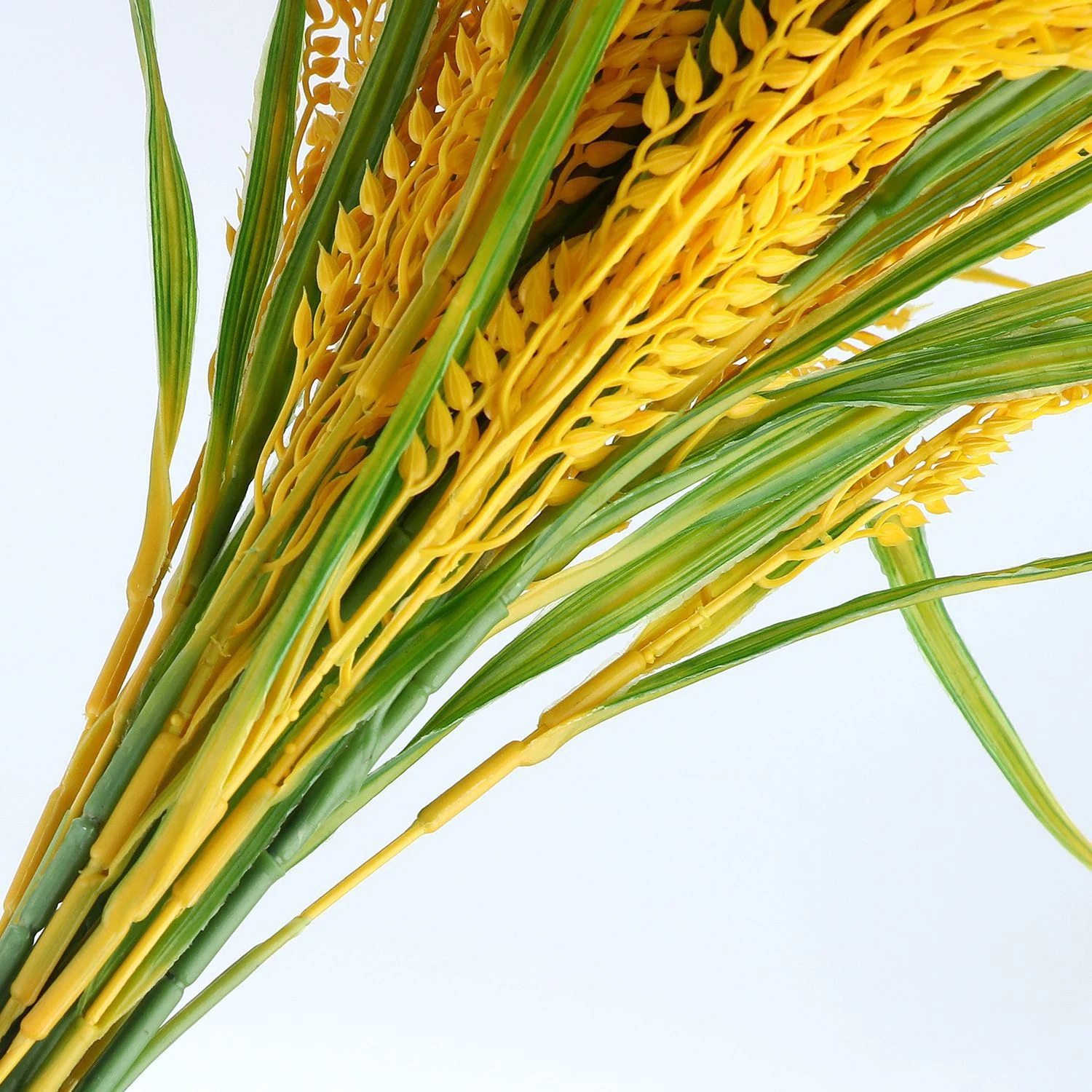 Close-up of golden artificial rice grains and green leaves