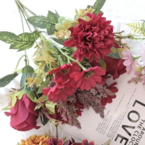 Close-up of burgundy red artificial rose, pompon flowers and filler sprigs