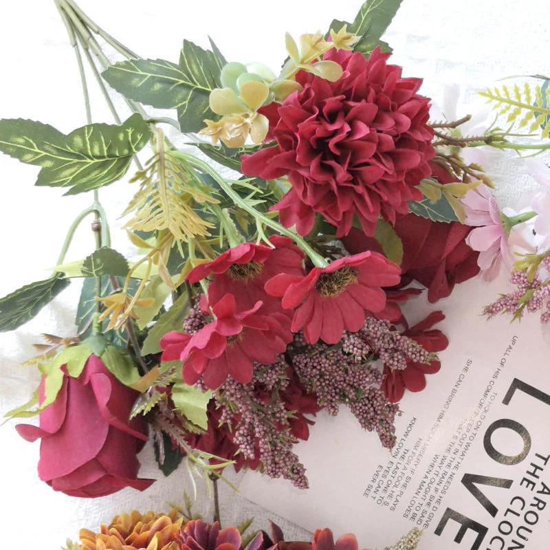 Close-up of burgundy red artificial rose, pompon flowers and filler sprigs