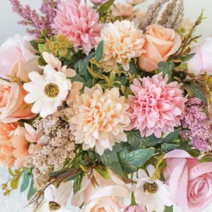 Close-up of peach and blush artificial roses, pompon blooms and daisy-like flowers