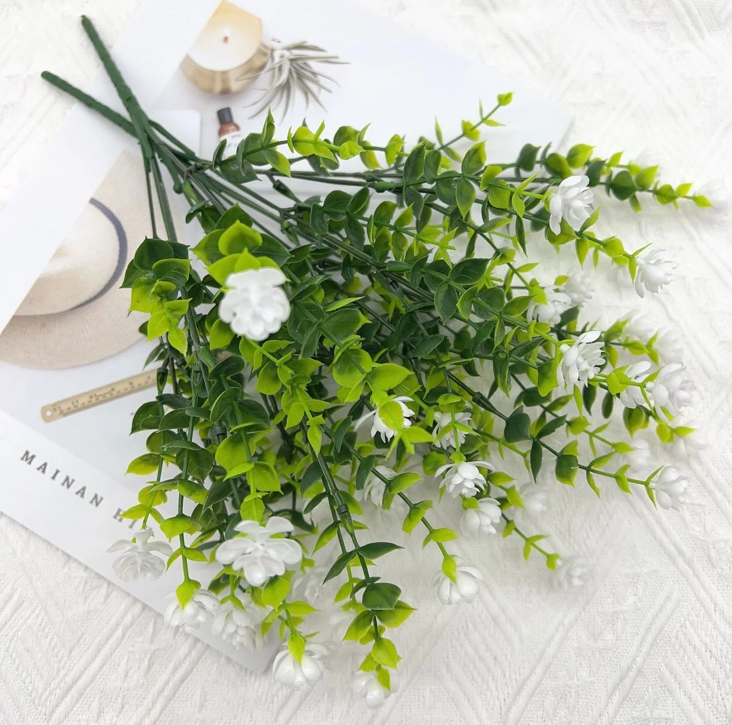 Artificial white mini flower bush in a styled flat-lay display