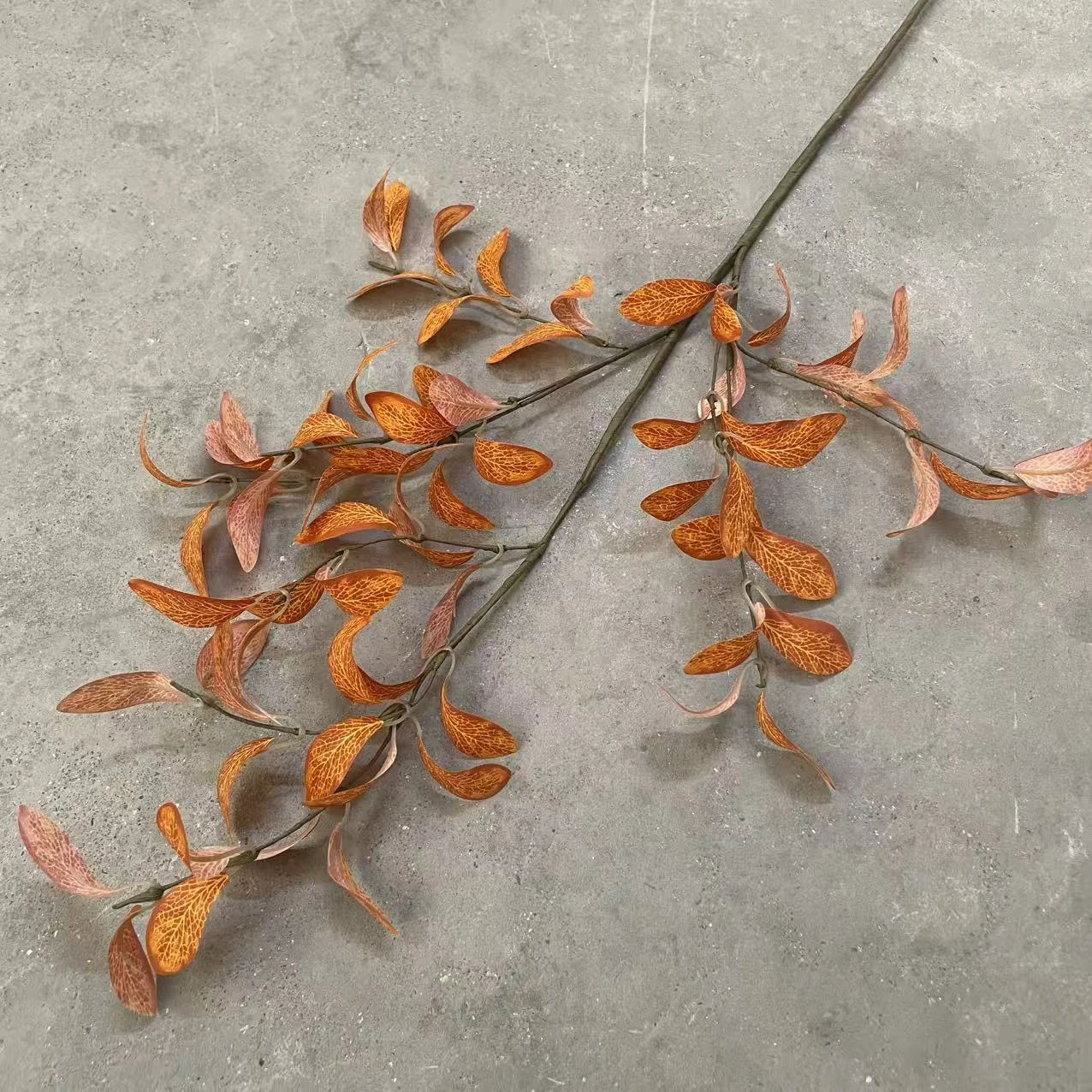 Angled view of burnt orange artificial eucalyptus spray branches