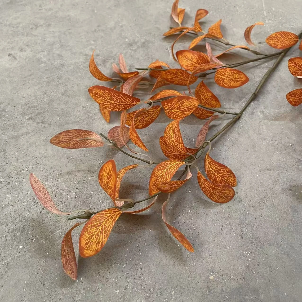 Close-up of burnt orange artificial eucalyptus leaves with visible veins