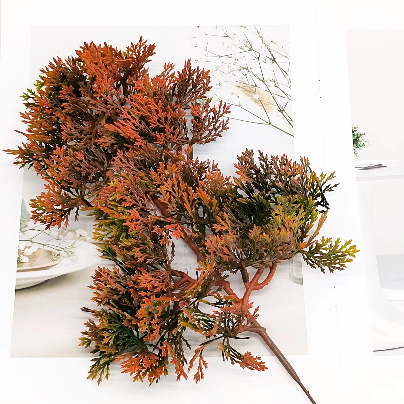 Flat-lay view of rust-orange artificial juniper branch