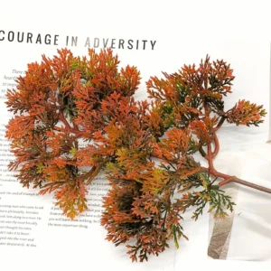 Rust-orange artificial juniper branch in a styled flat-lay display
