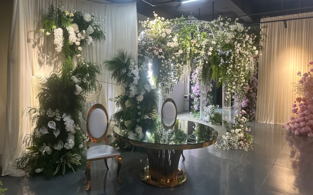 A round table and chairs surrounded by white and pastel artificial flower installations in the PJTL Foshan showroom.