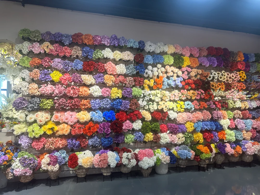 Rows of artificial hydrangeas in many colors displayed on a wall in the PJTL Foshan showroom.