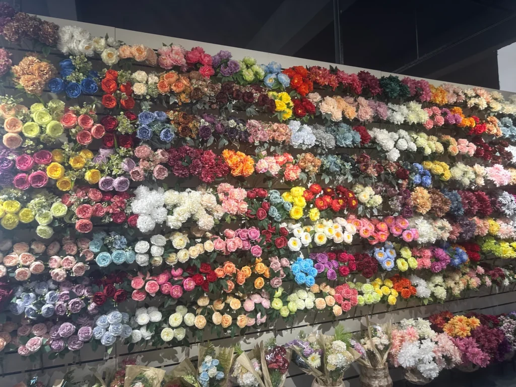 Rows of artificial flower stems in many colors displayed across a showroom wall.
