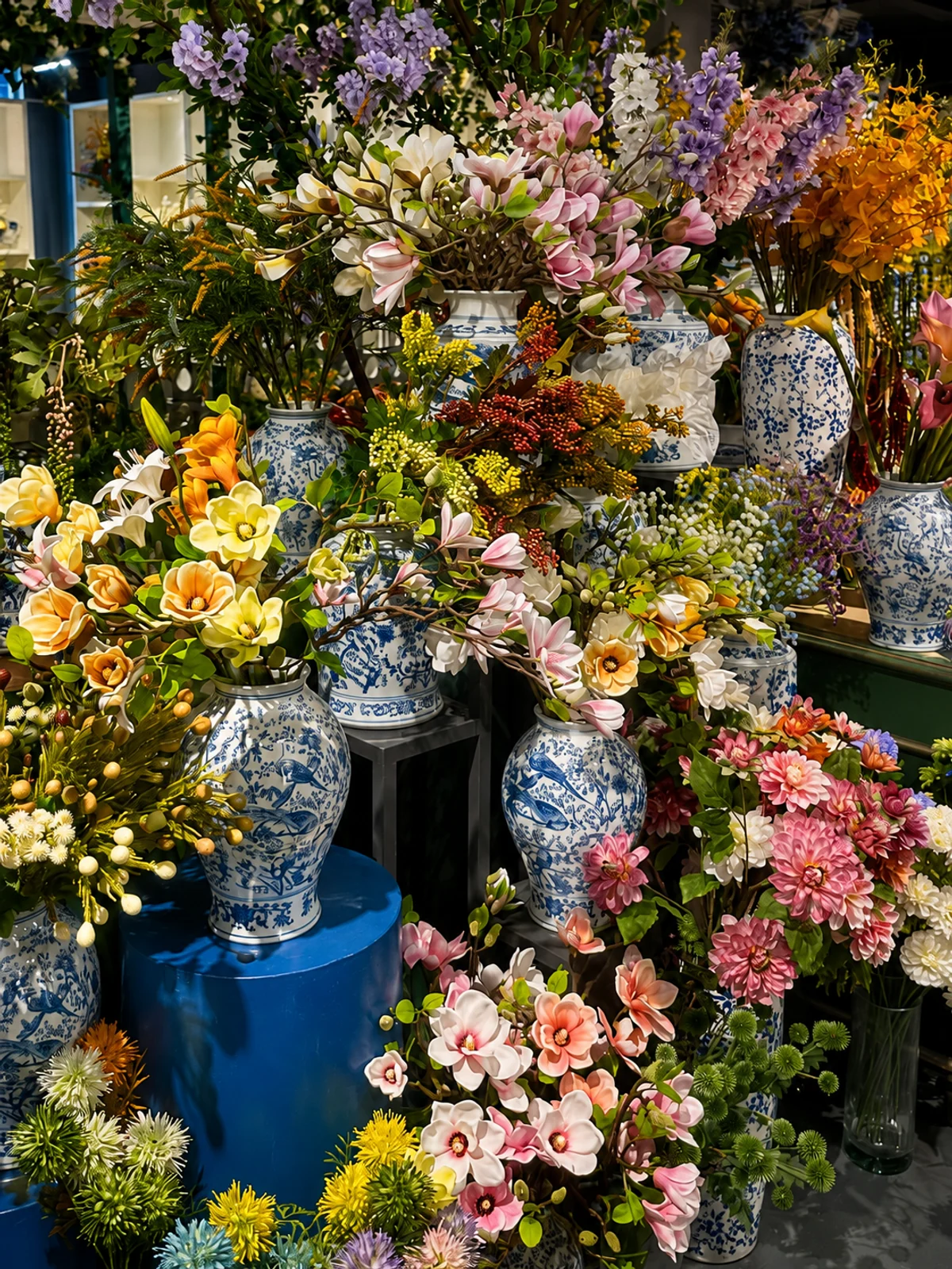 Real touch artificial flowers displayed in blue and white porcelain vases in the PJTL showroom.